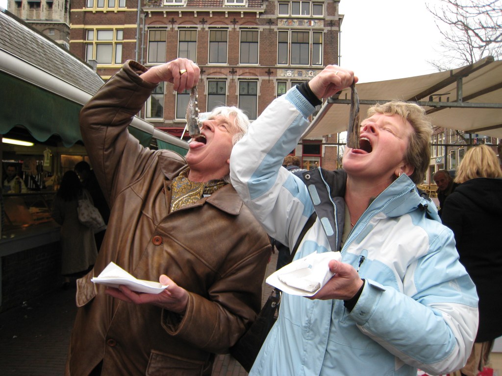 Dutch friends enjoying raw salted herring on Delft market place. The so-called "maatjes" are a very popular snack in the Netherlands (the Dutch fast food!) eaten at any time of the day in the particular Dutch way.