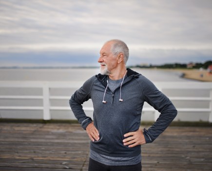 Middle-aged man facing to screen left is enjoying being active on the pier by the sea.