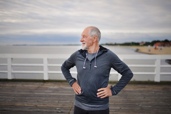 Middle-aged man facing to screen left is enjoying being active on the pier by the sea.