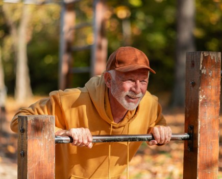 Active middle age man resting against a metal bar outdoors