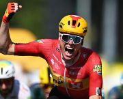 Cyclist Soren Waerenskjold wins at the Tour de France in a sprint finish. He is celebrating as he crosses the line, punching the air with his right arm and hand