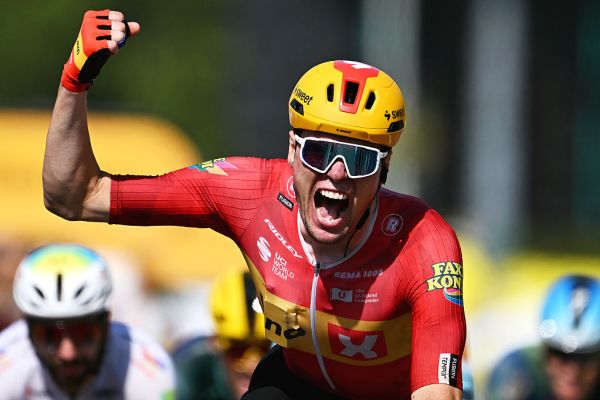 Cyclist Soren Waerenskjold wins at the Tour de France in a sprint finish. He is celebrating as he crosses the line, punching the air with his right arm and hand